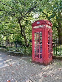 a red phone booth sitting in the middle of a park