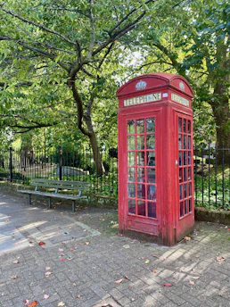 A cozy British street scene with autumn leaves and classic red phone booths.