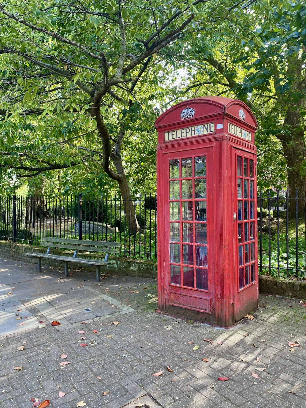 a red phone booth sitting in the middle of a park