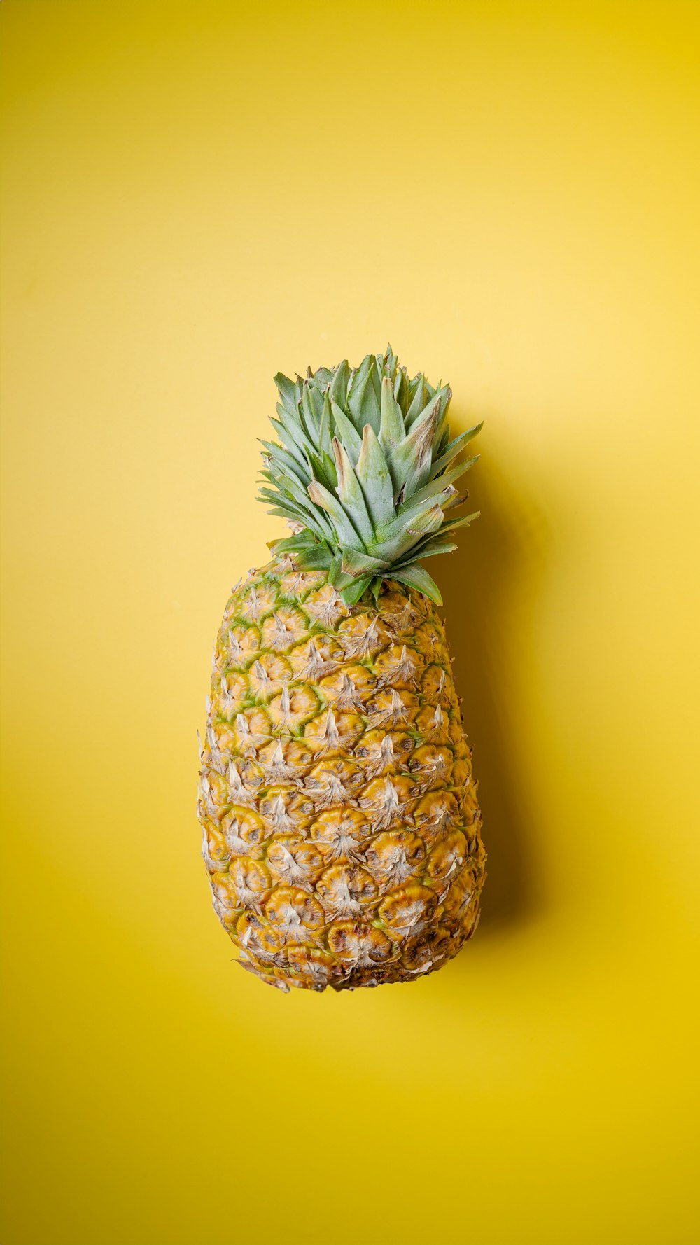 eine Ananas, die auf einer gelben Oberfläche sitzt
