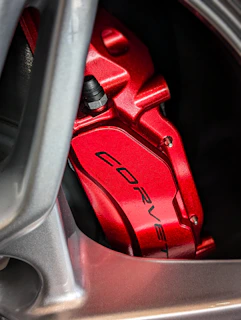 Close-up of a shiny red brake caliper mounted on a car wheel.