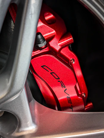 Close-up of a shiny red brake caliper mounted on a car wheel.