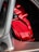 A close-up view of a vibrant red brake caliper with the word 'Corvette' inscribed on it. The caliper is nestled within the metallic framework of a car wheel.