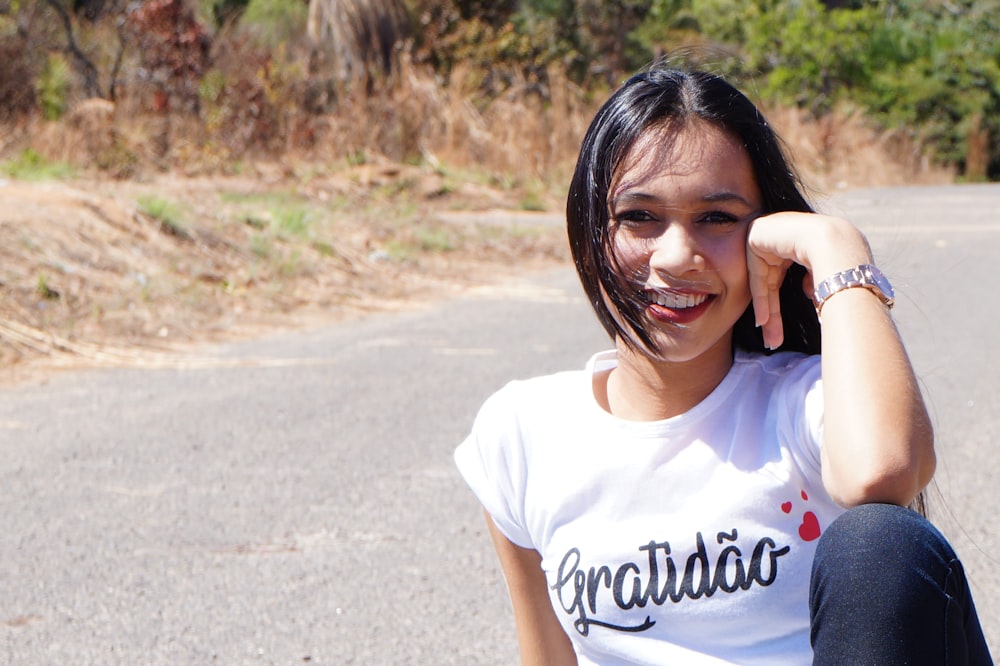 a young girl sitting on the side of a road