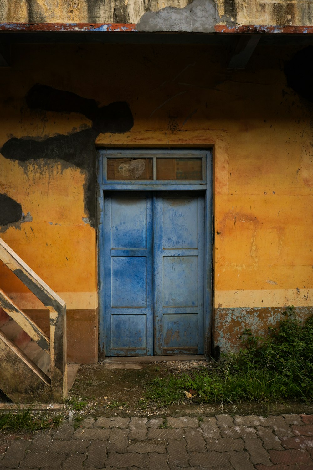 une porte bleue assise devant un bâtiment jaune
