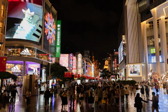 a crowd of people walking down a street next to tall buildings