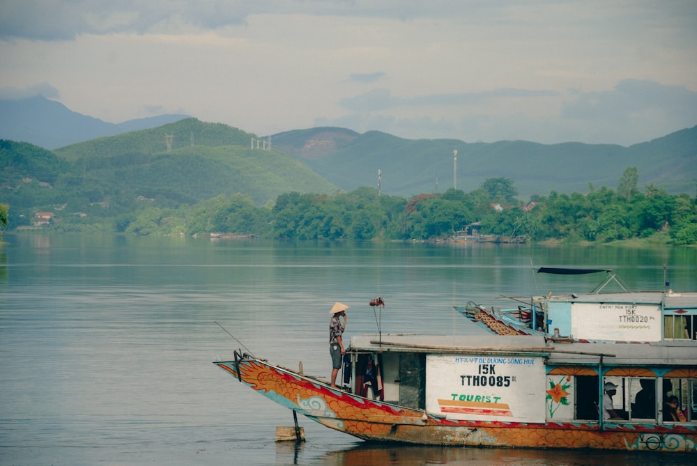 a man standing on top of a boat on a lake