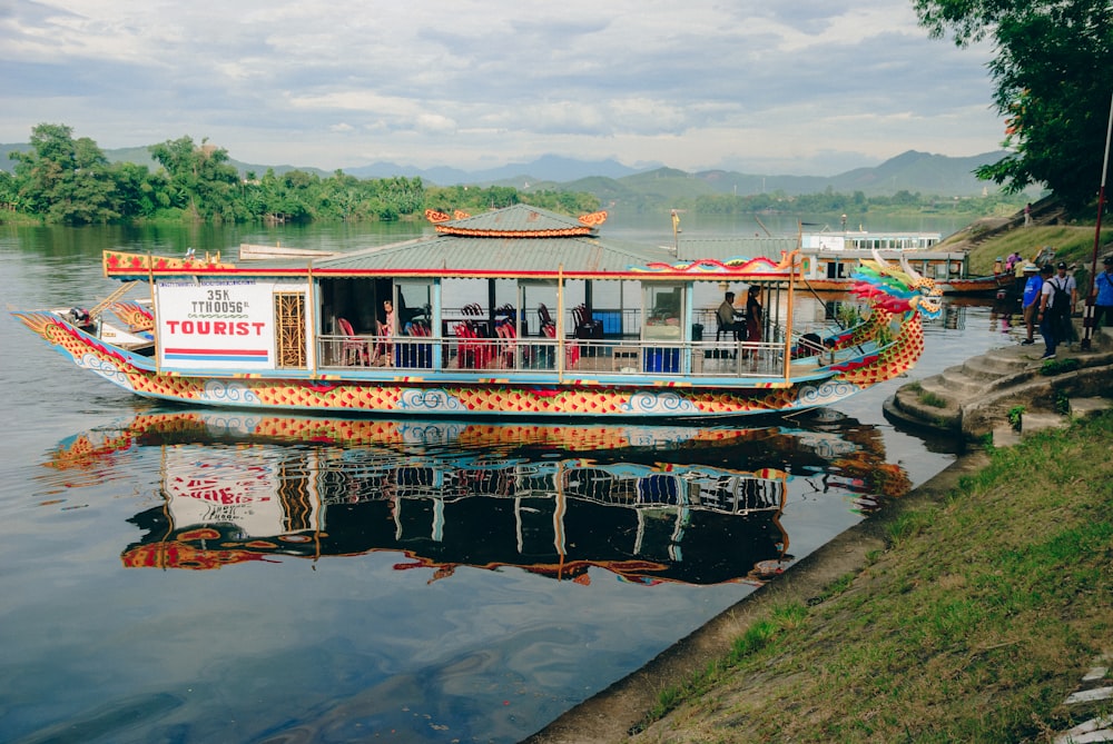 a colorful boat is on the water near a bank