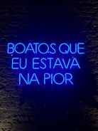 A neon sign displaying a phrase in Portuguese, illuminated in bright blue against a dark brick wall.