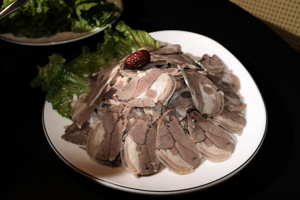 a white plate topped with meat and lettuce