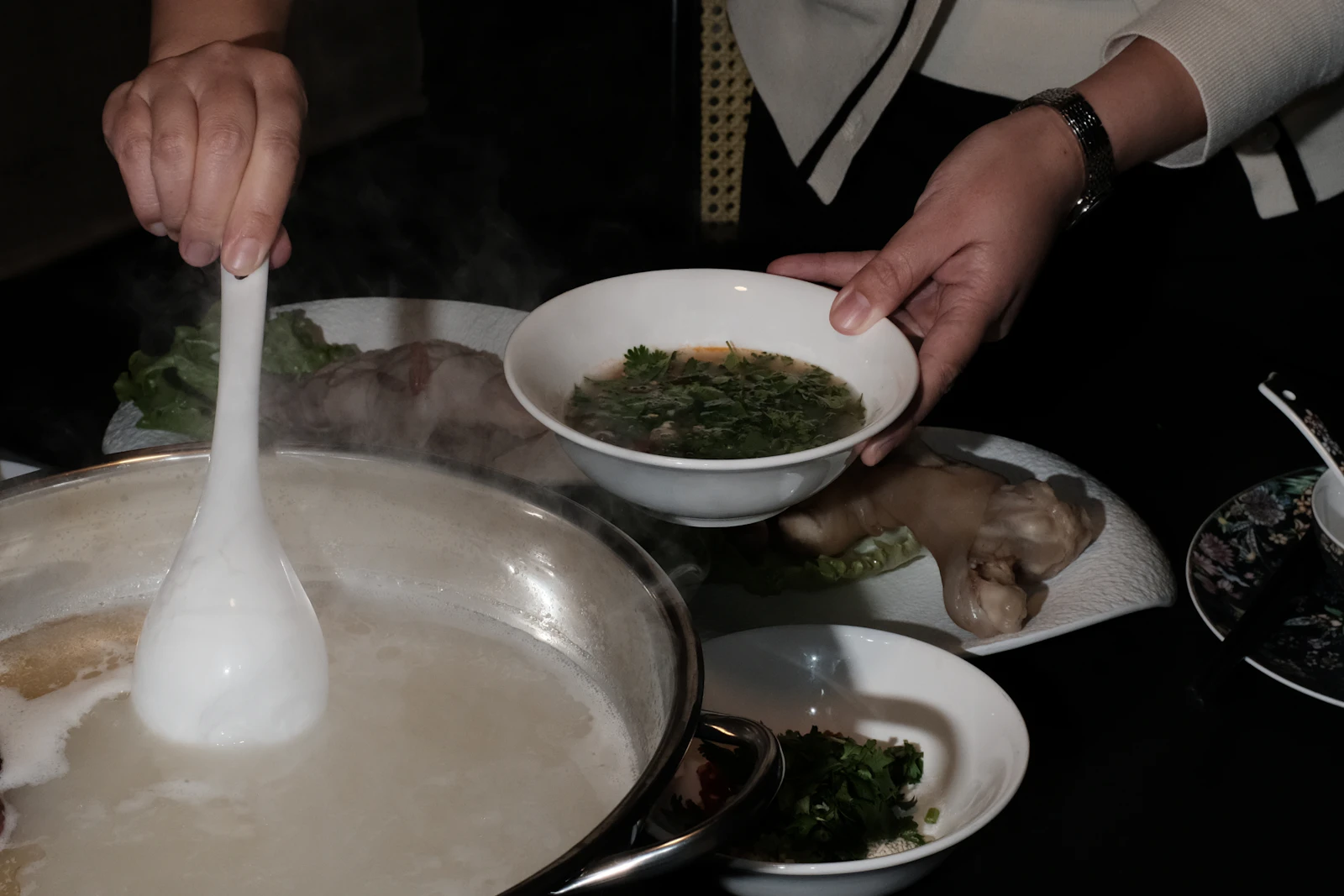 A bowl of hot soup being served at an East Asian dining table