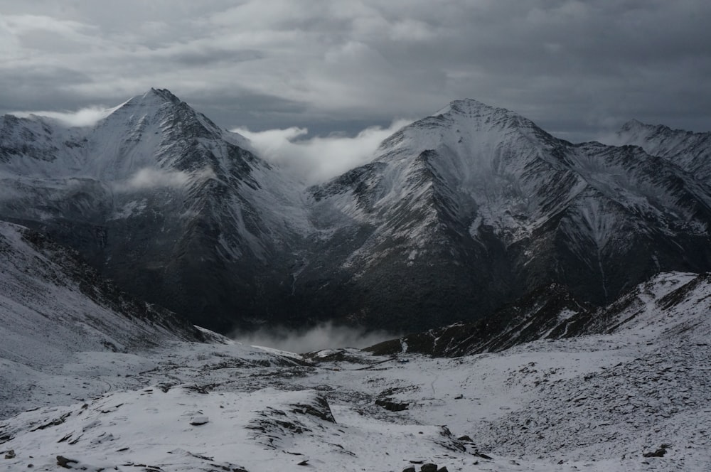 a mountain range covered in snow under a cloudy sky