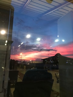 A warm sunset casting orange and purple hues over a busy international airport terminal filled with hopeful travelers.