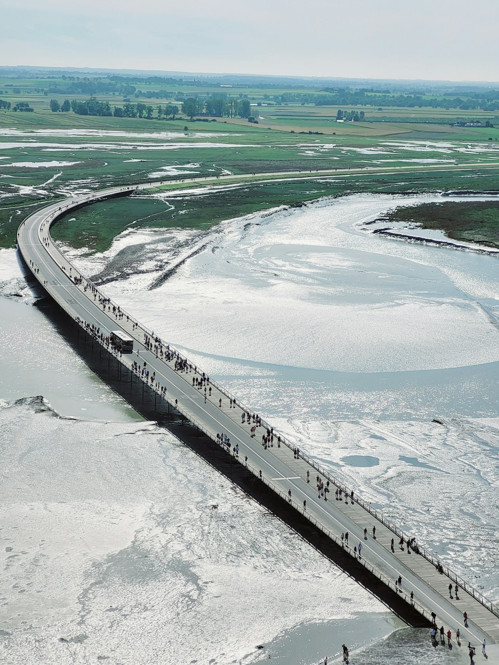 a group of people walking across a bridge over a river