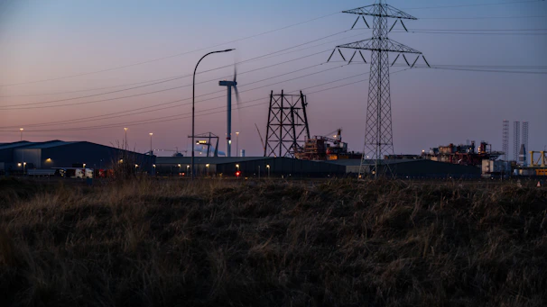 A panoramic shot of a sprawling renewable energy plant at dusk, with glowing green-lit infrastructure against a graphite sky.
