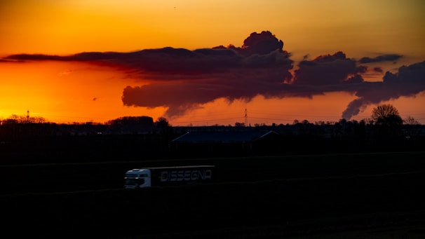 A delivery truck moving swiftly on a highway during sunset.