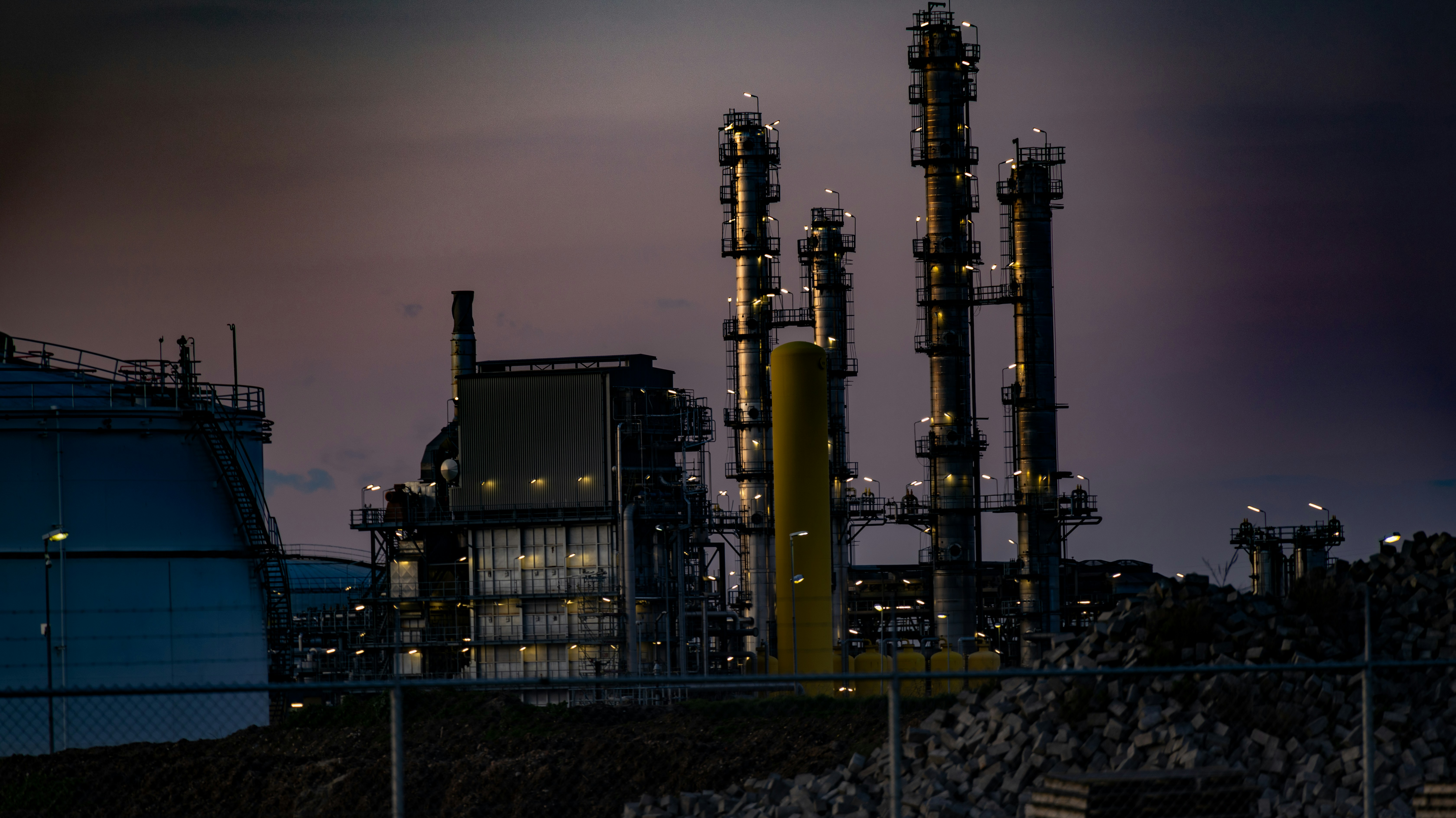 Industrial oil refinery at twilight, dramatic sky, energy infrastructure, complex industrial facility