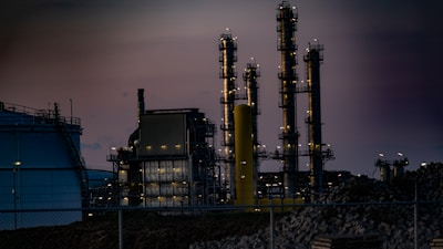 Industrial refinery complex with steaming towers during sunset.