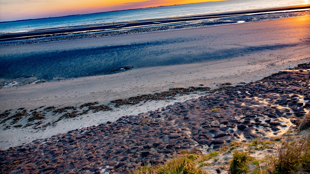 the sun is setting over the ocean on the beach