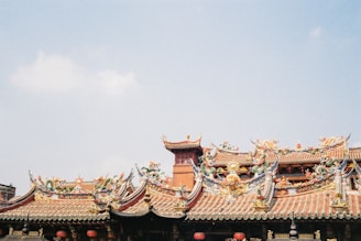 A traditional Taoist temple facade with red pillars and intricate carvings under a blue sky.