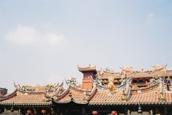 A traditional Taoist temple facade with red pillars and intricate carvings under a blue sky.