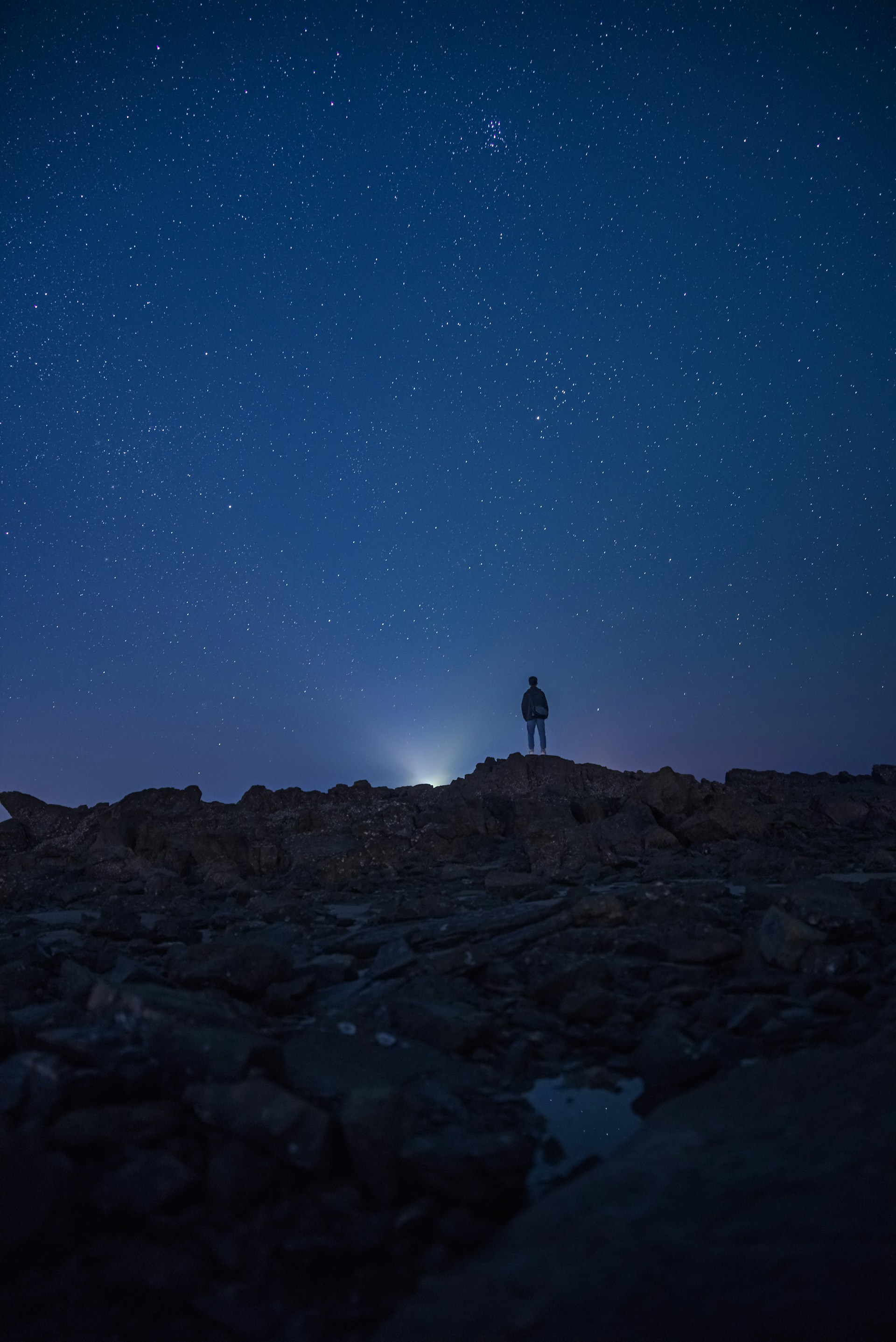 A shadowy figure standing beneath a swirling cosmic sky filled with stars and dark nebulae, embodying the gothic astro theme.