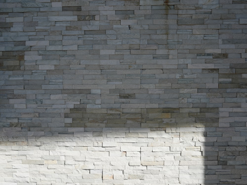 a person sitting on a bench in front of a brick wall