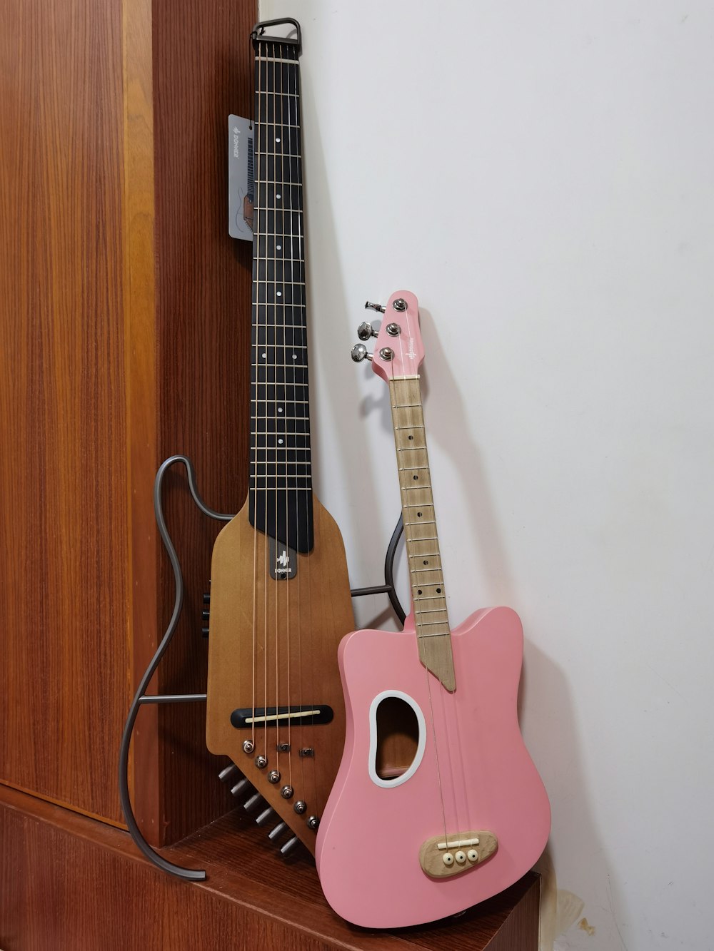 a pink ukulele and a pink ukulele sit on a shelf