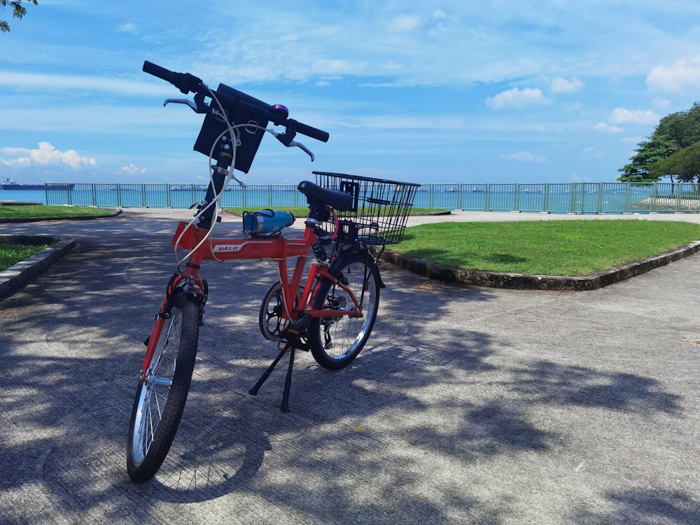 a red bike with a basket parked on the side of a road