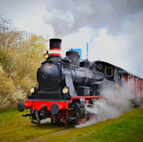 A vintage steam locomotive with billowing smoke on a sunny day