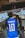 A person is wearing a blue soccer jersey with 'Neymar Jr' and the number '10' on the back, standing in front of a traditional shrine. The shrine features stone statues and rope decorations, with a white cloth adorned with red symbols.