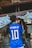 A person is wearing a blue soccer jersey with 'Neymar Jr' and the number '10' on the back, standing in front of a traditional shrine. The shrine features stone statues and rope decorations, with a white cloth adorned with red symbols.