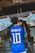 A person is wearing a blue soccer jersey with 'Neymar Jr' and the number '10' on the back, standing in front of a traditional shrine. The shrine features stone statues and rope decorations, with a white cloth adorned with red symbols.