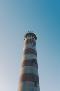 a red and white lighthouse with a blue sky in the background