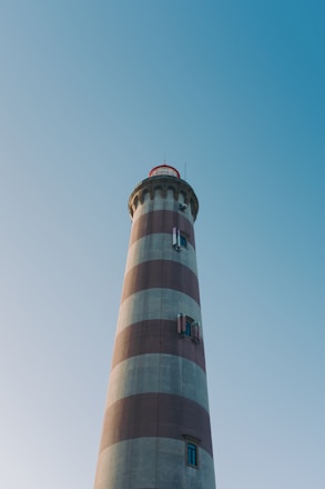 a red and white lighthouse with a blue sky in the background