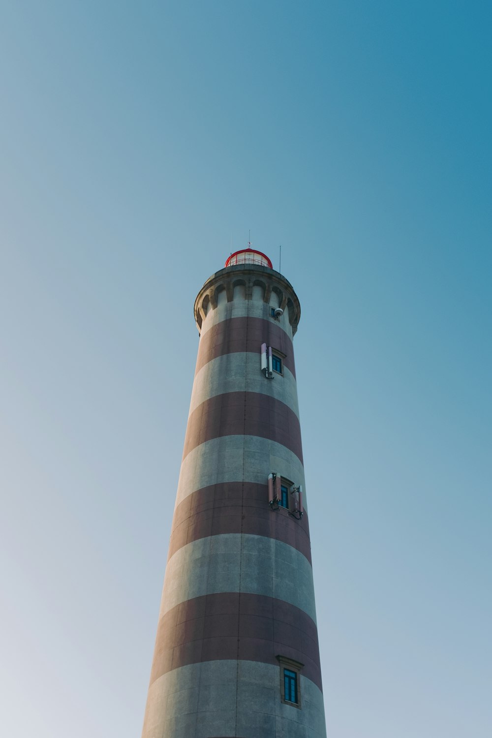 a red and white lighthouse with a blue sky in the background