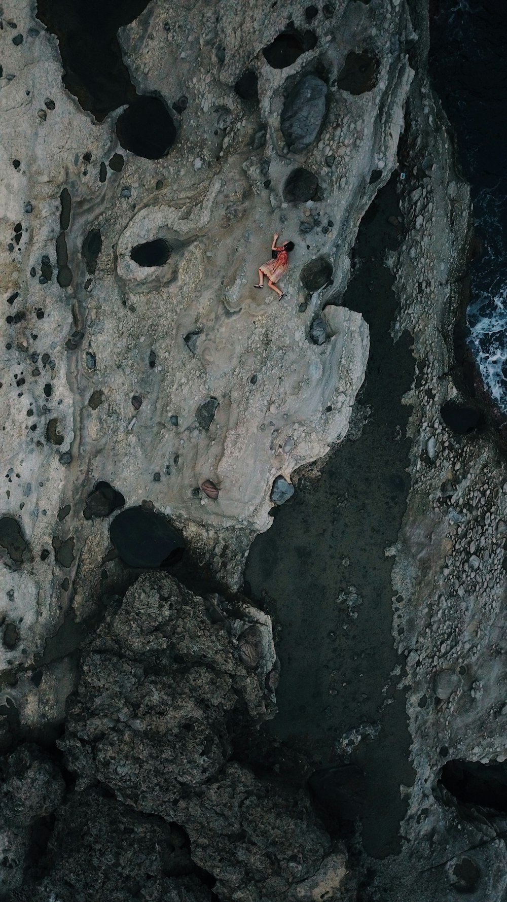 a person standing on top of a rocky cliff next to the ocean