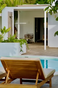 a wooden lounge chair sitting next to a swimming pool