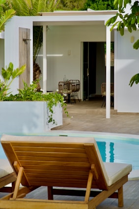 a wooden lounge chair sitting next to a swimming pool
