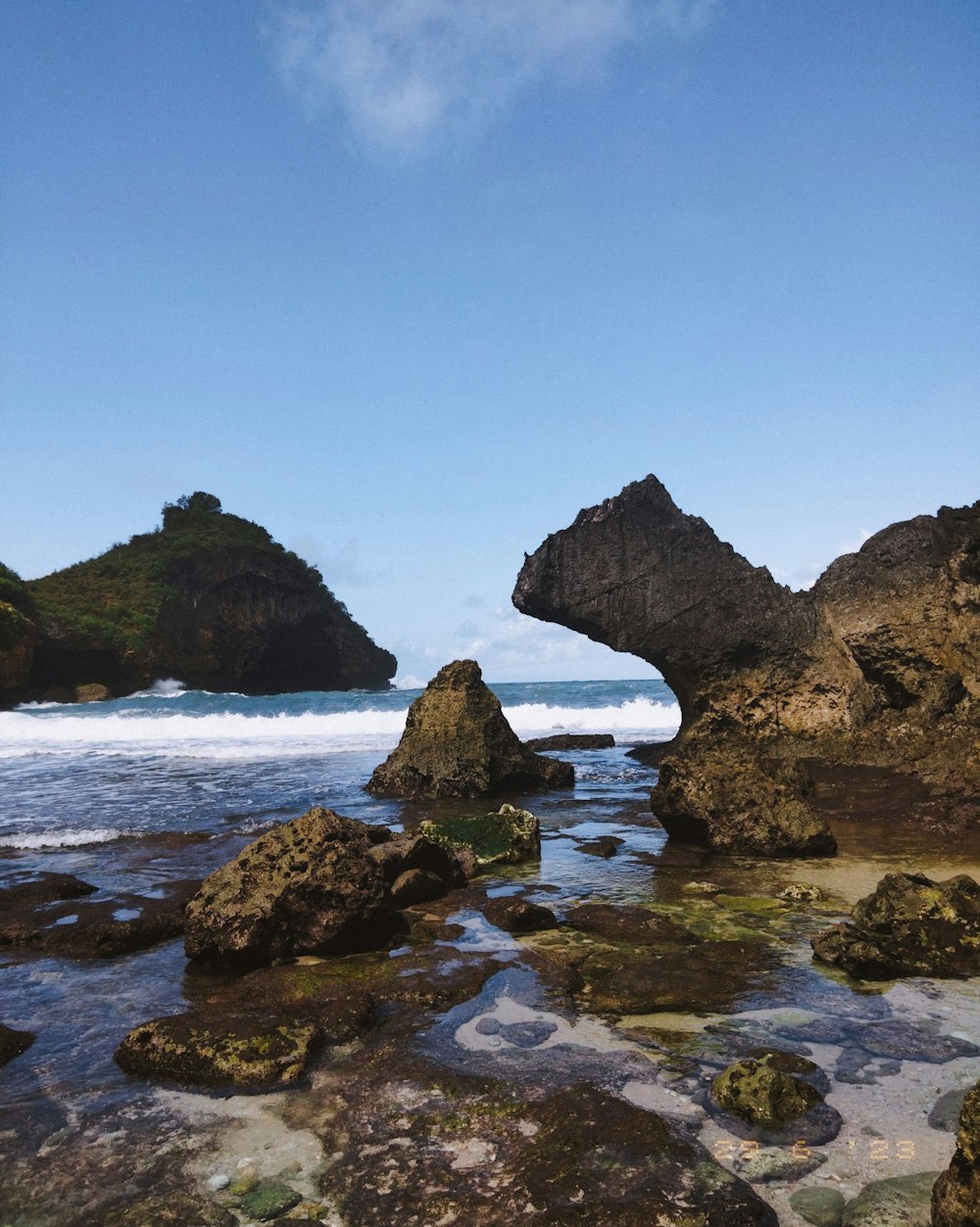 a rock formation in the water near a beach