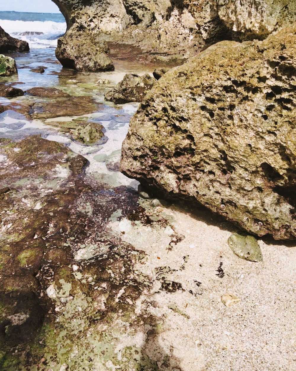 a rocky beach with a rock formation in the water