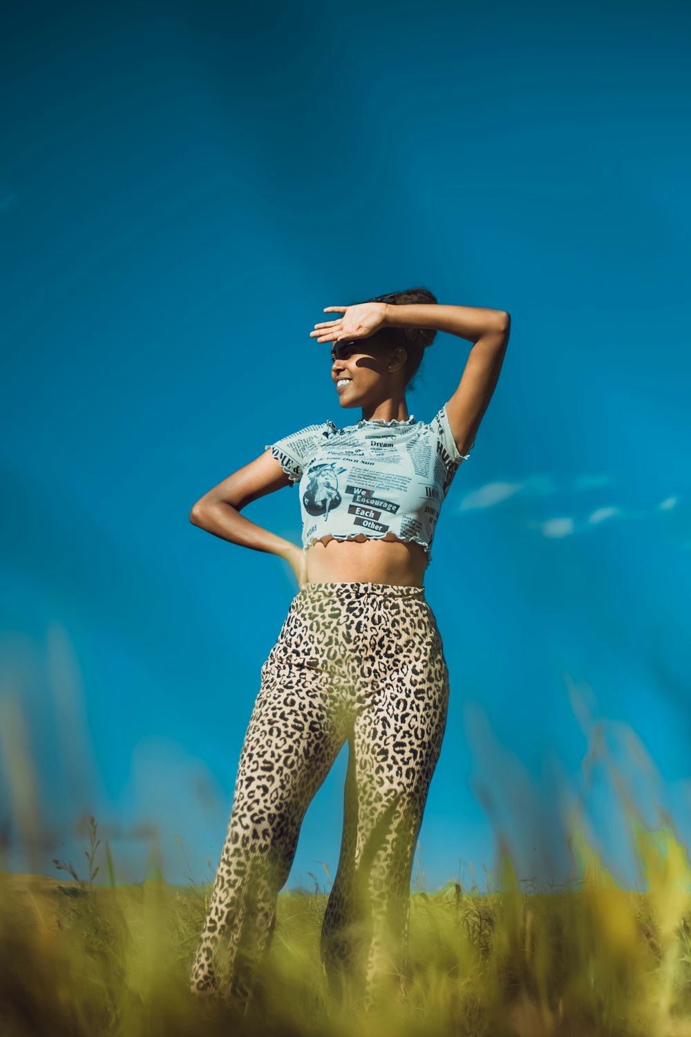 a woman standing in a field with her hands on her head