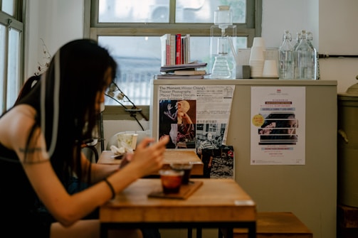 A lifestyle image showing a person using a vrindix phone stand while working at a cozy café table.