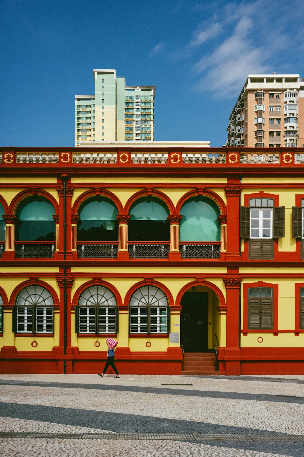 a person walking in front of a yellow and red building