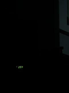 The red 11:11 LED clock illuminating a dark room with the movie poster in the background.