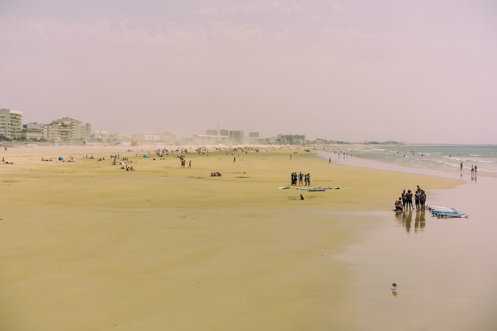 um grupo de pessoas em pé em cima de uma praia de areia