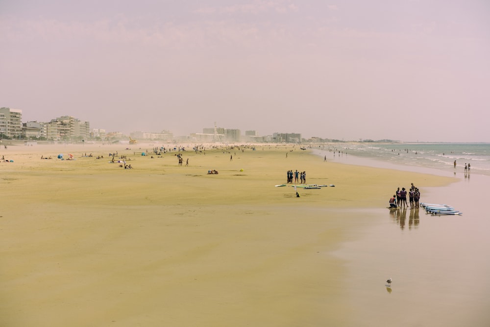 a group of people standing on top of a sandy beach