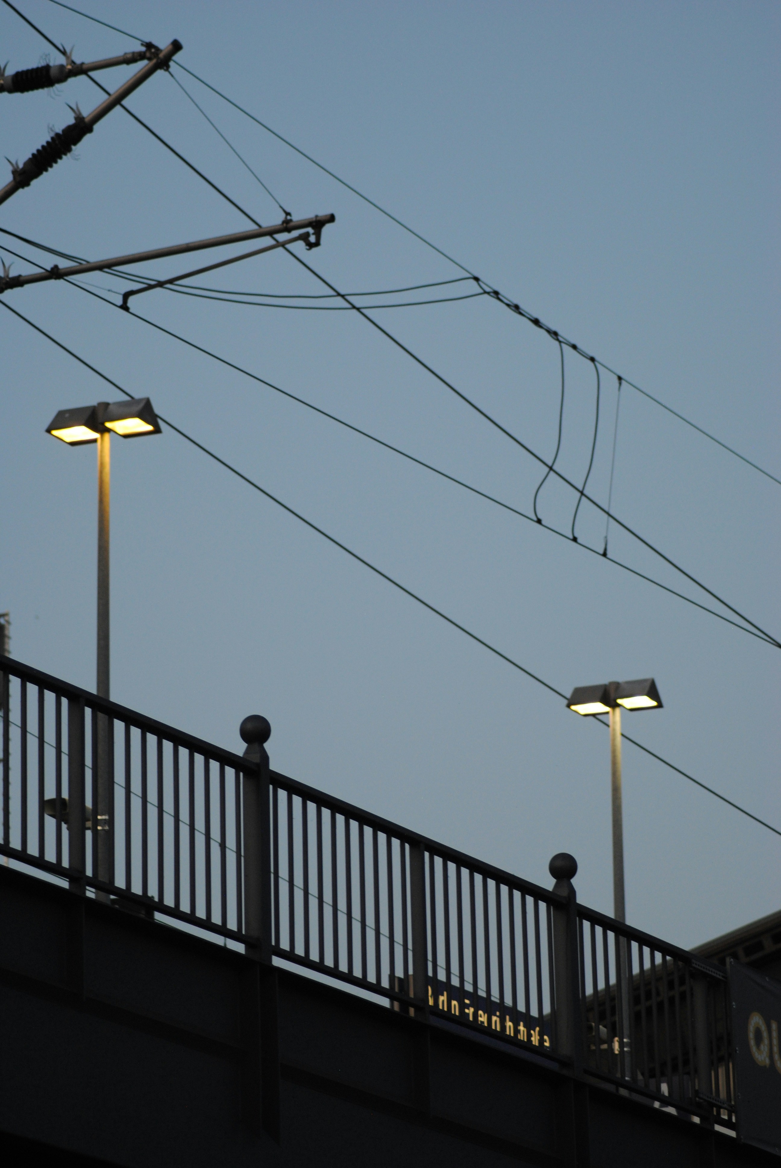 a bridge with two street lights and power lines above it