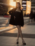 An elegant model posing confidently on a city street with soft yellow light filtering through.