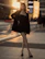 Moody photo of a powerful woman standing by a city skyline at night, dressed in a sleek black dress and silver heels.